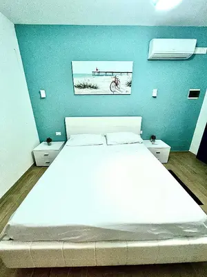 a bedroom with a white bed and a blue wall at B&B Santorini in Cinisi