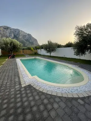 a swimming pool in a yard with mountains in the background at B&B Santorini in Cinisi