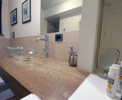 a bathroom with a glass sink and a toilet at Cozy Suite&Lodge Mondello beach in Palermo