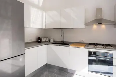 a white kitchen with white cabinets and a sink at Cube 67 - Villa in Palermo