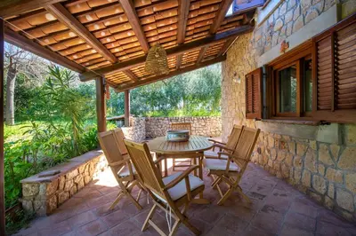 a patio with a table and chairs on a stone wall at Villetta Rosamarina by Wonderful Italy in Cefalù