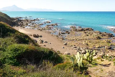 a beach with rocks and the ocean on a hill at Villetta Rosamarina by Wonderful Italy in Cefalù