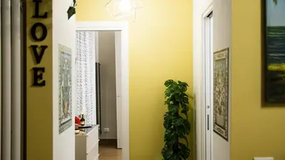 a hallway with yellow walls and a door with a plant at Le Maioliche Apartment in Palermo