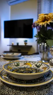 a table with two plates and a vase with flowers at Le Maioliche Apartment in Palermo