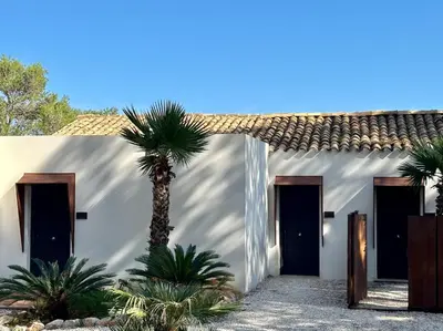 a white house with two doors and a palm tree at Araja Villa&Suite by Geocharme in San Vito lo Capo