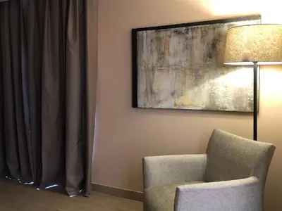a room with a chair and a painting and a lamp at Araja Villa&Suite by Geocharme in San Vito lo Capo