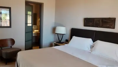 a bedroom with a white bed and a chair at Araja Villa&Suite by Geocharme in San Vito lo Capo