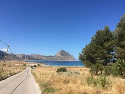 a road with a lake and mountains in the background at Màkari in Macari