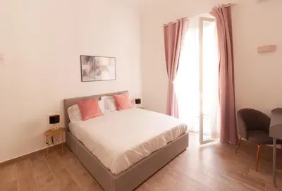 a bedroom with a bed with pink pillows and a window at Aragona15 Suites in Palermo