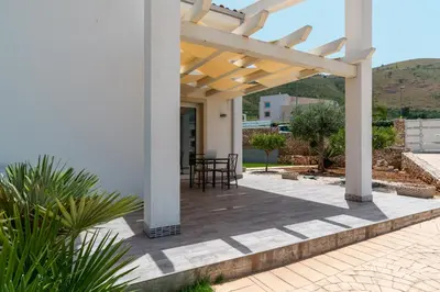 a pergola on a patio with a table and chairs at Nuova Villa a Scopello con piscina privata in Balata di Baida