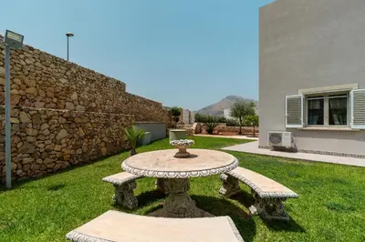 a stone table and benches in a yard at Nuova Villa a Scopello con piscina privata in Balata di Baida