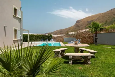 a backyard with a table and benches and a pool at Nuova Villa a Scopello con piscina privata in Balata di Baida