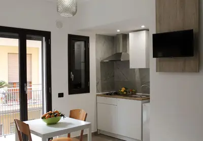 a white kitchen with a table and a table and a dining room at Case Carà 128, Appartamentini nel cuore di Bagheria, Piano Primo in Bagheria