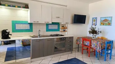 a kitchen with a sink and a stove and a table at Fronte Mare in Castellammare del Golfo