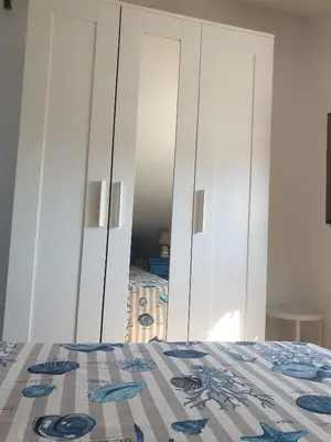 a bedroom with a bed and a white cabinet at Mansarda Marina in Campofelice di Roccella