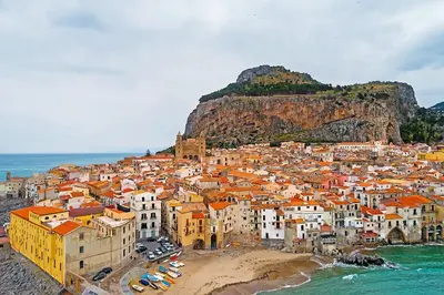 a group of buildings on a beach with a mountain at Mansarda Marina in Campofelice di Roccella