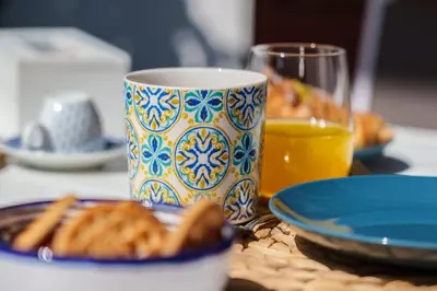 a table with a cup and plates of food and a glass of orange juice at Le Vele Mondello, villa a due passi dal mare in Mondello