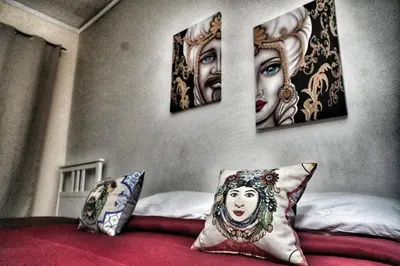 a bedroom with four paintings on the wall at La Casa del Moro - Al Politeama in Palermo