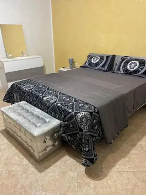 a bed with a black and white comforter and a bench at Casa vacanza Giusi in Palermo