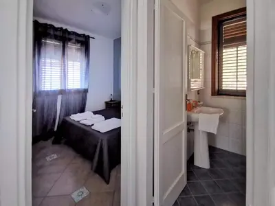 a bedroom with a bed and a sink in a bathroom at VILLA BIFAMILIARE SCOPELLO in Scopello