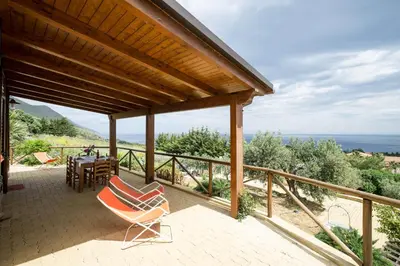 a patio with two chairs and a table and the ocean at VILLA BIFAMILIARE SCOPELLO in Scopello