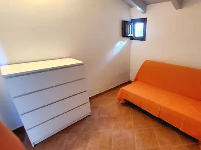 an orange couch and a cabinet in a room at VILLA BIFAMILIARE SCOPELLO in Scopello