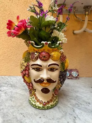 a statue of a face with a bunch of flowers at Bella Sicilia in Palermo
