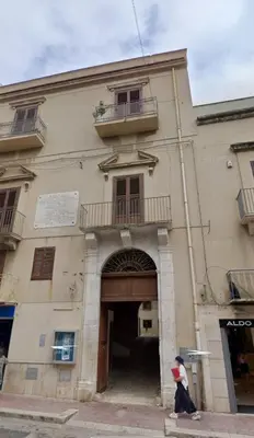 a person sitting in front of a building at Attico in centro città in Alcamo