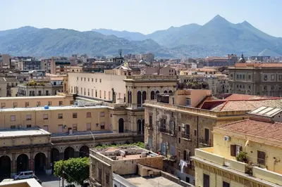 a view of a city with mountains in the background at CENTRAL STATION APARTMENTS - Fanale Rentals in Palermo