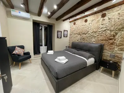 a bedroom with a bed and a stone wall at Tommy's rooms in Palermo
