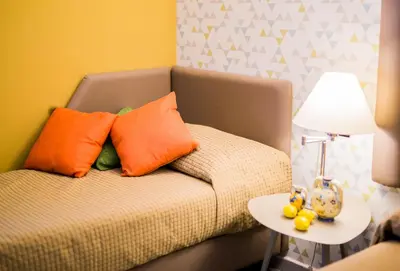 a couch with orange pillows and a table with a lamp at Albergo Athenaeum in Palermo