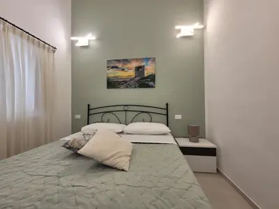 a bedroom with two beds and a painting on the wall at JEY STUDIO_INDEPENDENT SEAFRONT APARTMENT in Terrasini