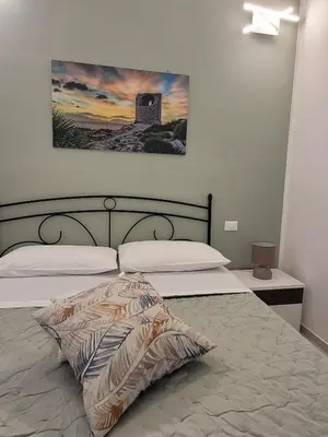 a bedroom with two beds and a painting on the wall at JEY STUDIO_INDEPENDENT SEAFRONT APARTMENT in Terrasini