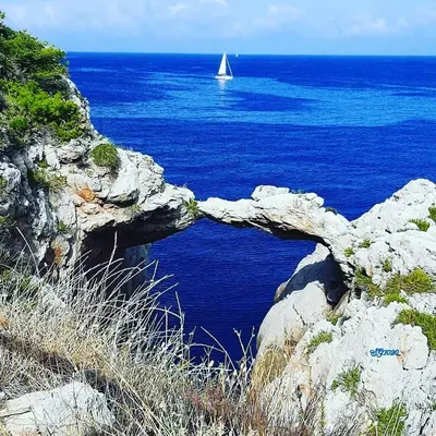 a sail boat in the ocean with a rock formation at Terra D'Aspra in Bagheria