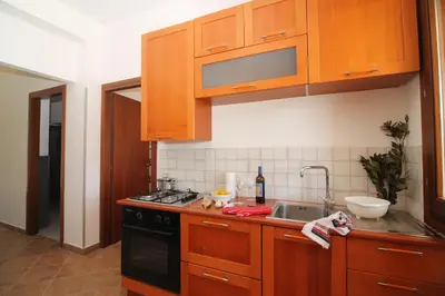 a kitchen with wooden cabinets and a sink and a stove at CASA IL LIMONE 300M MARE PARK e GIARDINO PRIV WIFI in San Vito lo Capo