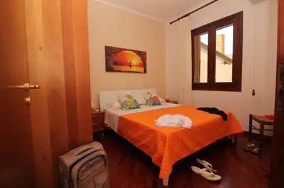 a bedroom with a bed with an orange blanket at CASA IL LIMONE 300M MARE PARK e GIARDINO PRIV WIFI in San Vito lo Capo