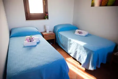 two beds in a room with blue sheets and flowers on them at Case Vacanza Sabbia Rosa in San Vito lo Capo