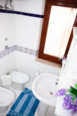 a bathroom with two toilets and a sink and a window at Case Vacanza Sabbia Rosa in San Vito lo Capo