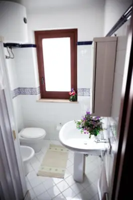 a bathroom with a sink and a toilet and a window at Case Vacanza Sabbia Rosa in San Vito lo Capo