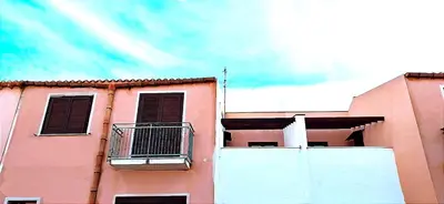 a pink building with a balcony on top of it at Case Vacanza Sabbia Rosa in San Vito lo Capo