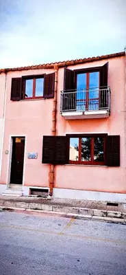 a pink building with windows and a balcony at Case Vacanza Sabbia Rosa in San Vito lo Capo