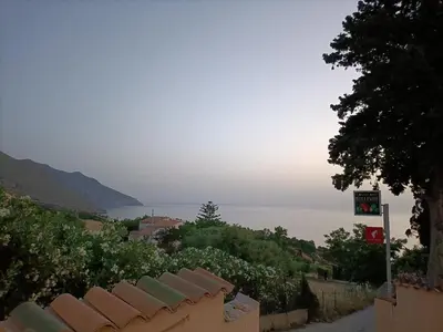a view of the ocean from a hill with a town at La casetta a Scopello in Scopello
