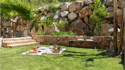 a picnic table in the grass with a stone wall at VILLA OLIMPIA 6&2, Emma Villas in Castellammare del Golfo
