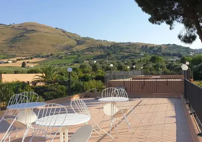 a patio with two tables and chairs and a hill at Scopello Home in Castellammare del Golfo
