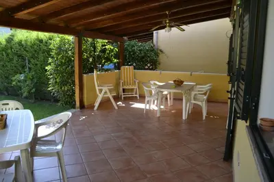 a patio with chairs and a table and a table and chairs at Villa in recidence a 100 metri dal mare con servizio di piscina a 100 metri vicino Cefalu in Campofelice di Roccella