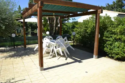 a patio with a table and chairs under a pergola at Villa in recidence a 100 metri dal mare con servizio di piscina a 100 metri vicino Cefalu in Campofelice di Roccella