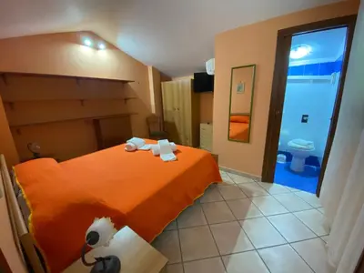a bedroom with an orange bed with towels on it at Villa in recidence a 100 metri dal mare con servizio di piscina a 100 metri vicino Cefalu in Campofelice di Roccella