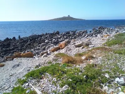 a rocky island in the ocean with a lighthouse on it at Villetta Isola in Isola delle Femmine