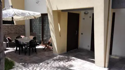 a patio with a table and chairs and an umbrella at Villetta Isola in Isola delle Femmine