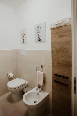 a bathroom with a toilet and two pictures on the wall at Casa Vacanze Galati in Palermo